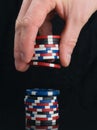 The gamblers hand, on a black background, adds game chips to the bet