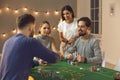 Group of young friends awaiting for card from deck during betting and playing poker Royalty Free Stock Photo