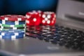 Gambling chips and red dice on laptop keyboard background Royalty Free Stock Photo