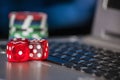 Gambling chips and red dice on laptop keyboard background Royalty Free Stock Photo