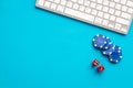 Gambling, online games. Chips and dices near keyboard on blue background top-down copy space