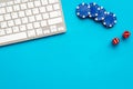 Gambling, online games. Chips and dices near keyboard on blue background top-down copy space