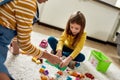 Game. Caucasian cute little girl spending time with african american baby sitter. They are playing with toys, sitting on Royalty Free Stock Photo