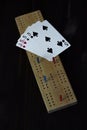 Playing cards and cribbage board on black background