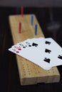 Playing cards and cribbage board on black background