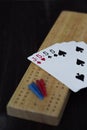 Playing cards and cribbage board on black background