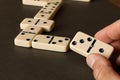 A game of dominoes on a dark table . The concept of the game of dominoes. Man`s hand with a Domino. Close up. Royalty Free Stock Photo