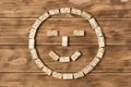 A game of dominoes. A smiley face made of Domino pieces on a wooden table