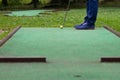 a game of mini-golf, a view from the hole at the time of striking a yellow ball with a stick Royalty Free Stock Photo