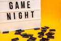 Game night text on lightbox with black dominoes on yellow background, table game Royalty Free Stock Photo