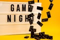 Game night text on lightbox with black dominoes on yellow background, table game