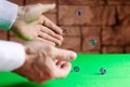 At the game table with a green cloth there is a game of craps. The player rolls the dice on the table surface