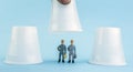 Game of wits with three glasses of plastic, figures thumbnail of men, conceptual image Royalty Free Stock Photo