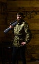 Gamekeeper concept. Hunter, brutal hipster on strict face with gun ready for hunting. Man with beard wears camouflage