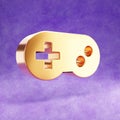 Gamepad icon. Gold glossy joystick symbol isolated on violet velvet background.