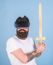 Gamer concept. Hipster on serious face enjoy play game in virtual reality. Guy with head mounted display holds sword Royalty Free Stock Photo