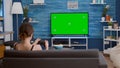 Gamer girl playing console video games with wireless controller on green screen tv relaxing on couch Royalty Free Stock Photo
