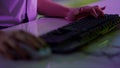 Gamer hands typing keyboard in neon cyberspace closeup. Video gaming club night.