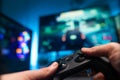 The gamer is playing a video game with friends. In his hands he has a modern joystick. Also in front is a large TV screen, Royalty Free Stock Photo