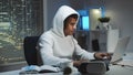 Gamer in white hoodie and with headphones playing games on computer in the evening