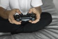 Gamer in white tshirt holding a gamepad in hands. Man hands playing a video game with a black controller. Play a video Royalty Free Stock Photo