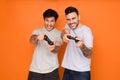 Gamers. Two mates playing video games, orange background