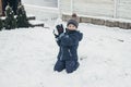 Games in the snow, winter holidays, family vacations. Cute caucasian boy playing in the snow in the yard of the house Royalty Free Stock Photo