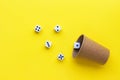 Gaming dice and cardboard cup on yellow background. Playing cube with numbers. Items for board games. Flat lay top view with copy