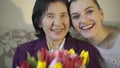 Gandmother with flowers and granddaughter smiling on the camera. Slowly