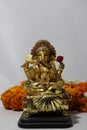 Ganesha made from brass with yellow marigold flower and white background, the son of Uma Devi god in Hinduism and Brahmanism.