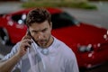 Gangster call phone. Angry man chatting on phone near car on night urban street. Dangerous aggressive man with phone Royalty Free Stock Photo