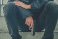 Gangster men holding a gun sitting on stairs. Young men peaceful sitting with a gun on him hand alone