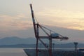 Gantry crane in boom up position painted red with white stripes during sunset in container terminal.