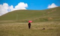 GANZI TIBETAN SICHUAN CHINA -AUGUST-19-2016 :Tibetan monkLama with red umbrella walking on the green hill and meditation