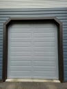 Garage door Grey color with dark blue metal siding with silver trim