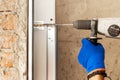 Garage doors installation. Worker drills a hole for the bolt.