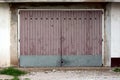 Garage doors made of dilapidated wooden boards with metal plate rain protection mounted on cracked old wall Royalty Free Stock Photo