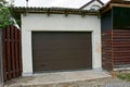 Garage facade with a closed brown door and part of the fence in the street