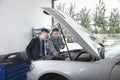 Garage Mechanic Explaining to Customer and Looking at Car with Open Hood Royalty Free Stock Photo