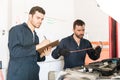 Male Worker Checking Motor Oil While Coworker Writing In Clipboard Royalty Free Stock Photo