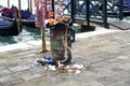 Garbage bin full of litter on the Grand Canal promenade in Venice, Italy .