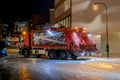 Garbage collecting truck moves along city street. Dark time of day. Royalty Free Stock Photo