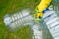 Hand in yellow glove holding big empty plastic bottles. Grass on a background Royalty Free Stock Photo