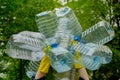 Hands in yellow gloves holding big empty plastic bottles. Grass on a background