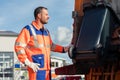 Garbage collection worker putting bin into waste truck Royalty Free Stock Photo