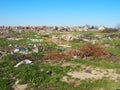 Garbage dump near the village. Chaotic unofficial dump. Plastic, bags, paper, glass, biological waste. Green grass next to dirt.