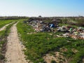 Garbage dump near the village. Chaotic unofficial dump. Plastic, bags, paper, glass, biological waste. Green grass next to dirt.