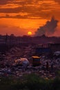 garbage dump at sunset, silhouetting the heaps of waste
