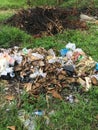 Garbage pile in garden. Rubbish heap in garden among vegetation. Throw trash anywhere