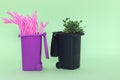 Garbage pot with a green fresh plant and other with plastic straw on a green background.